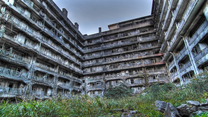 Abandoned concrete apartment building overgrown with grass