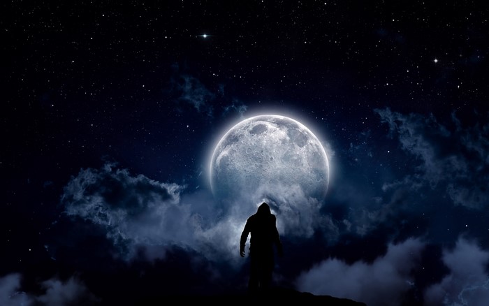 Silhouette of a figure against a large moon and starry night sky