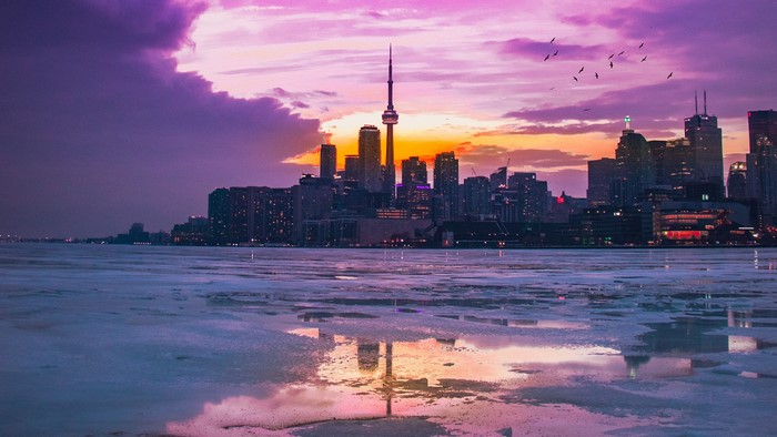 Toronto cityscape with CN Tower at sunset over frozen water