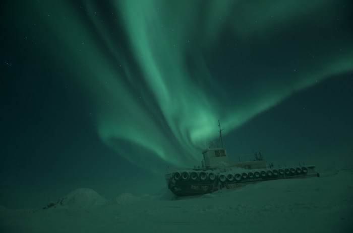 Abandoned tugboat under aurora borealis in Alaska