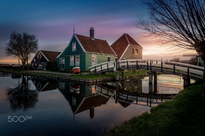 Dutch village houses reflected in canal at sunset