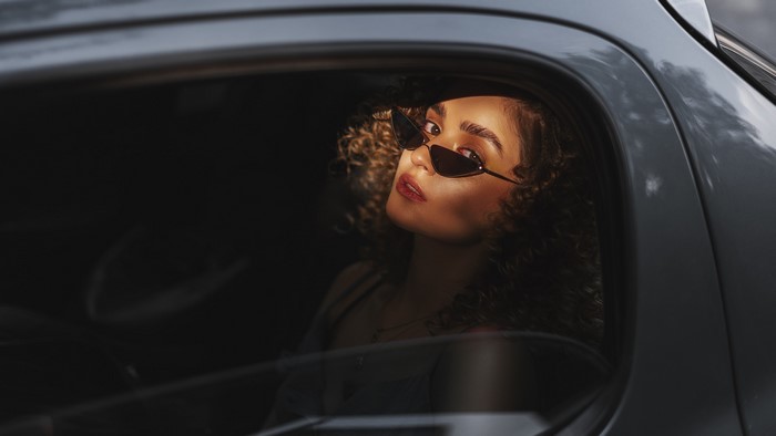 Woman with curly hair and sunglasses in a car