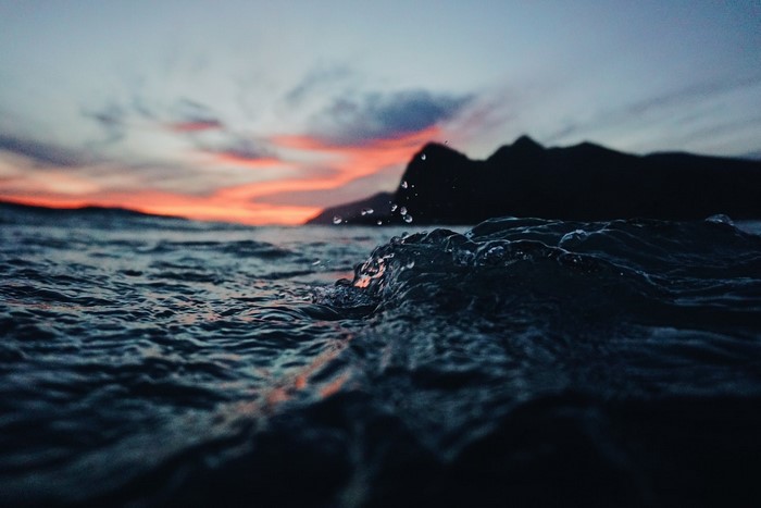 Water surface with mountains and sunset clouds