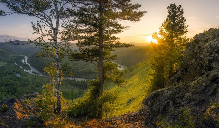Sunset over a winding river valley with trees and rocks