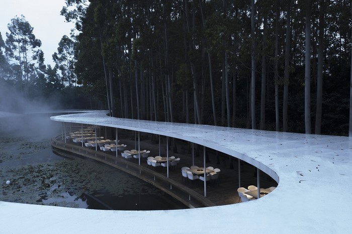 Modern curved restaurant by a lake with trees