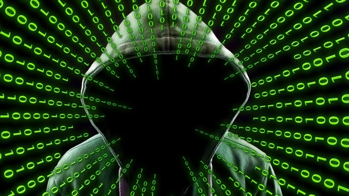 Anonymous hacker in a hoodie surrounded by binary code