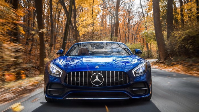 Blue Mercedes-AMG GT driving on a road in fall