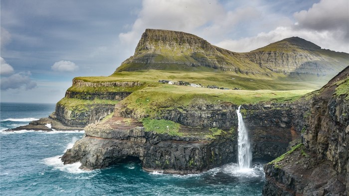 Waterfall cascading from green cliffs into the sea