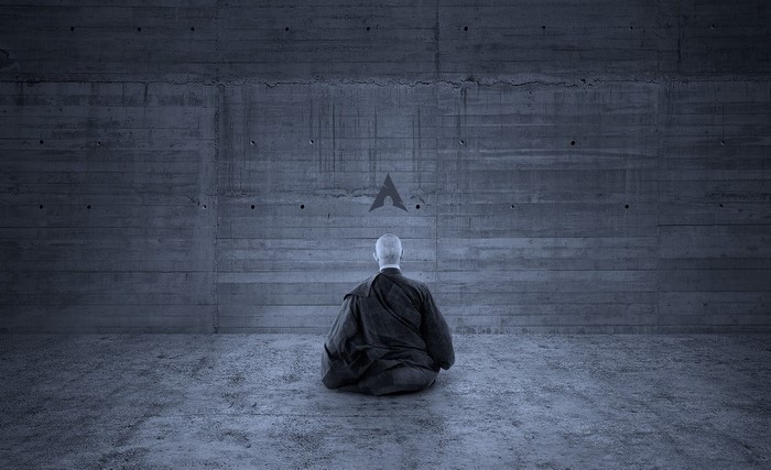 Man meditating in front of Arch Linux logo on concrete wall