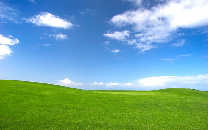 Green hills under a blue sky with clouds
