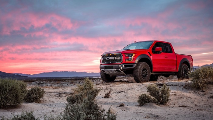 Red Ford F-150 Raptor pickup truck at sunset in desert