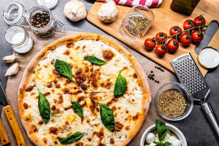 Four cheese pizza with basil, tomatoes, and garlic