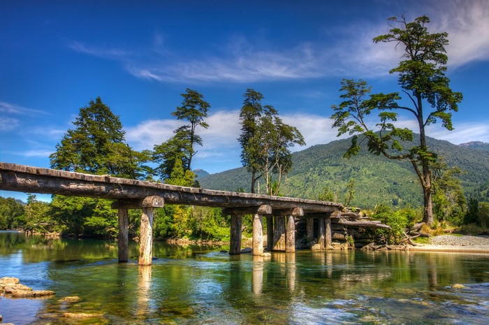 Wooden bridge over a river in Chile with trees and mountains