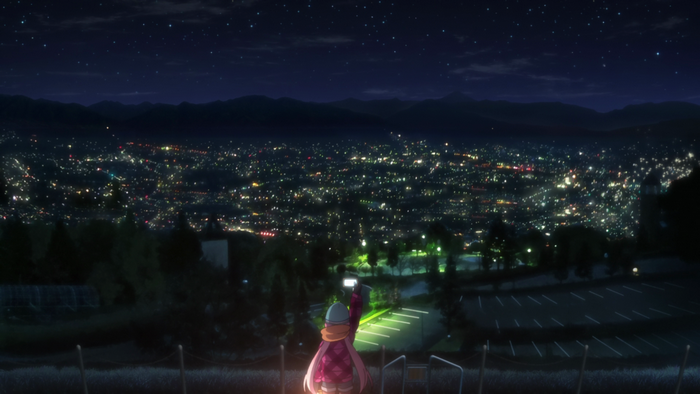 Girl taking a photo of a city at night from a hill