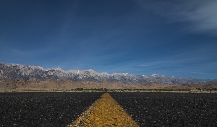 Road leading to snow-capped mountains in Death Valley, USA