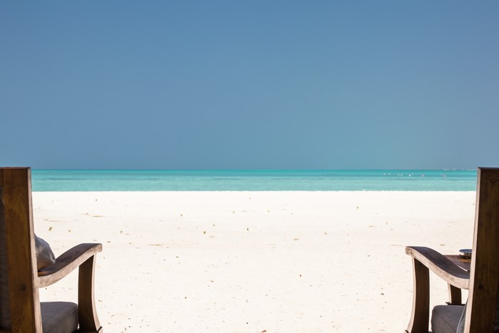 Two chairs on a tropical beach overlooking the ocean