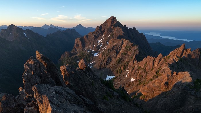 Jagged mountain peaks at sunset with distant water