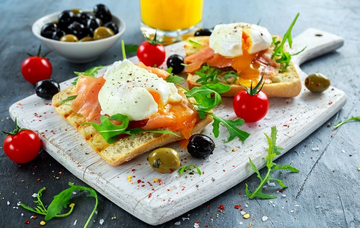 Poached eggs with salmon on toast with tomatoes and olives