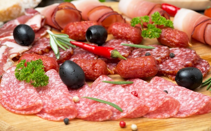 Charcuterie board with salami, olives, and chili peppers