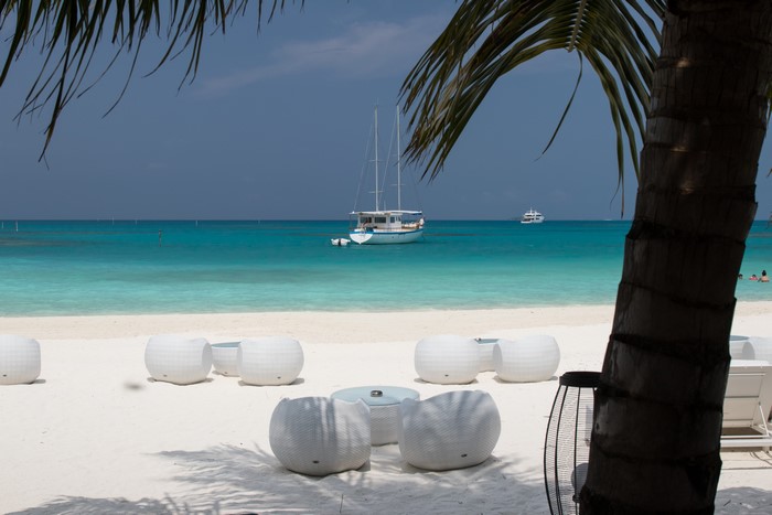 Tropical beach with white furniture and sailboats