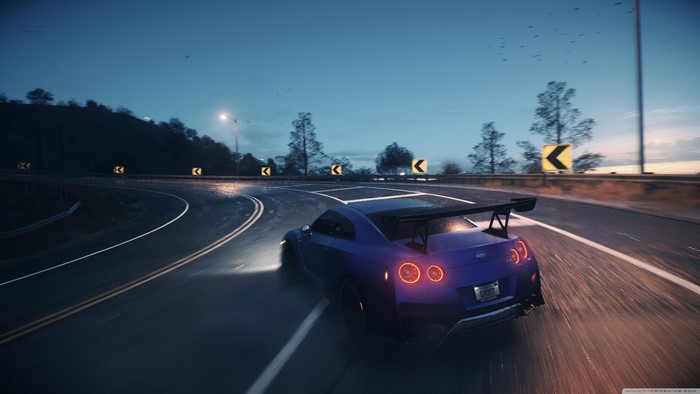 Blue Nissan GT-R racing on a wet road at dusk