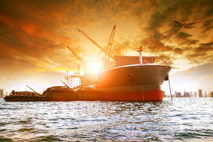 Cargo ship and airplane at sunset