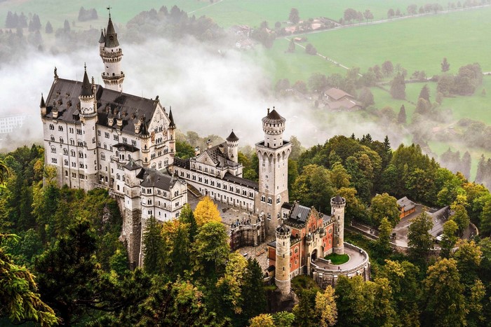 Neuschwanstein Castle in Germany surrounded by trees and fog