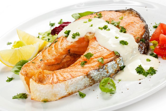 Salmon steaks with sauce, lemon, and salad