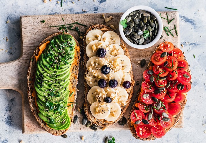 Avocado, banana, and tomato toasts with pumpkin seeds