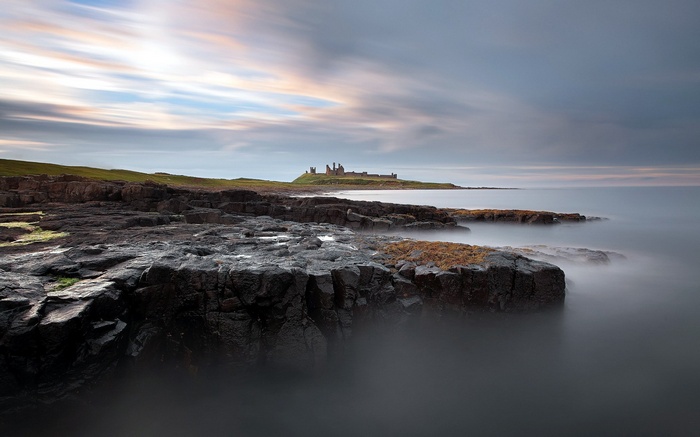 Castle on a rocky island coast with long exposure sea