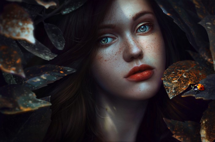 Woman with blue eyes and freckles surrounded by leaves