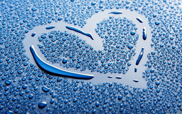 Heart shape formed by water drops on a blue surface
