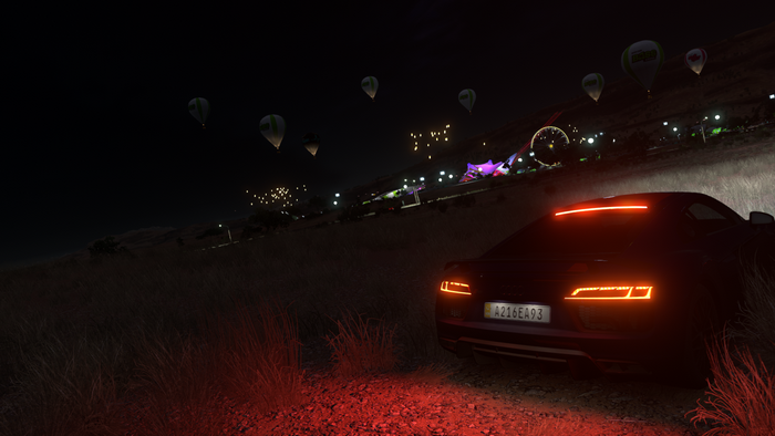 Car at night with hot air balloons and Ferris wheel