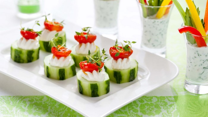 Cucumber bites with cream cheese, cherry tomatoes, and herbs