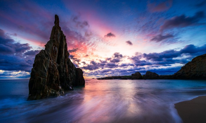 Dramatic sunset over rocky coastline with ocean waves