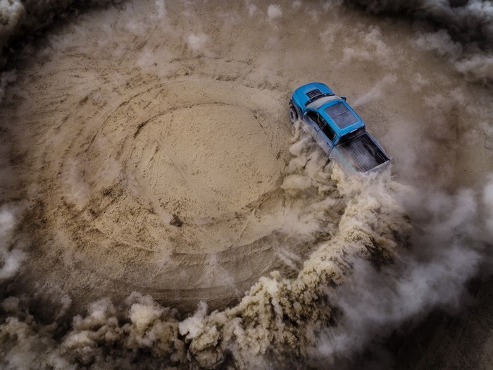 Blue Ford F-150 Raptor drifting in dirt