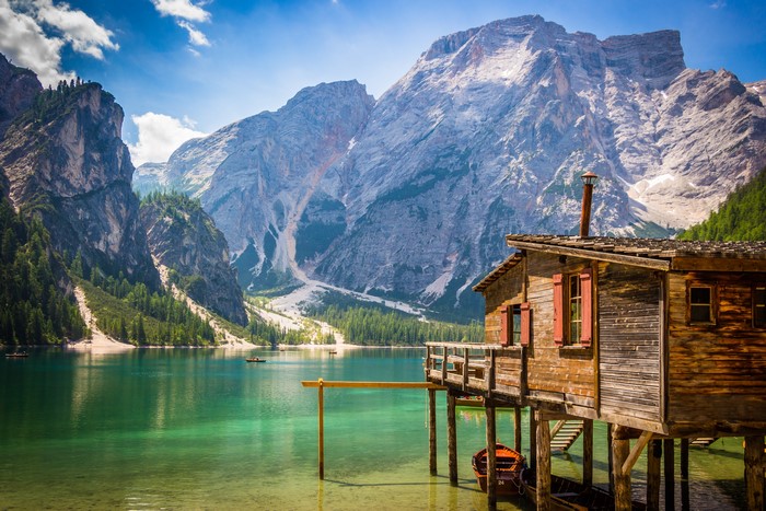Wooden cabin on a lake with mountains