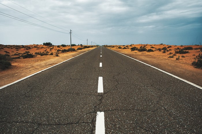 Desert road with power lines under a cloudy sky