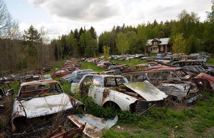 Junkyard with abandoned cars and a house