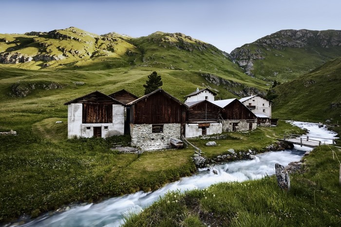Mountain landscape with old stone and wooden houses by a stream