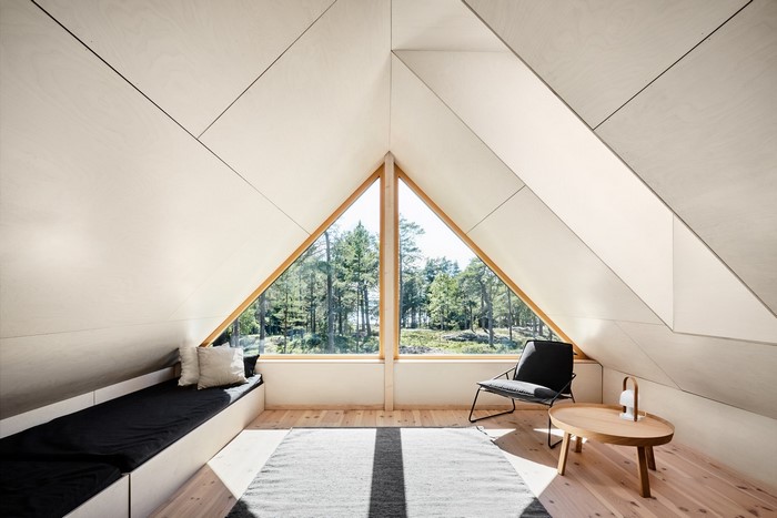 Modern attic room with triangular window and forest view
