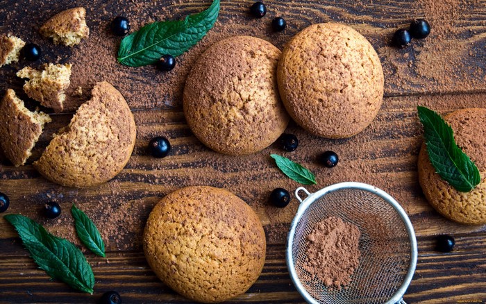 Oatmeal cookies with berries and cocoa powder on a wooden surface