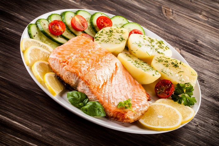 Salmon with potatoes, lemons, cucumbers, and tomatoes
