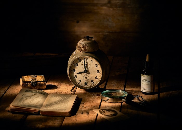 Vintage alarm clock, old book, and magnifying glass