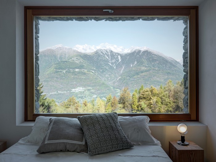 Bedroom with mountain view through stone-framed window