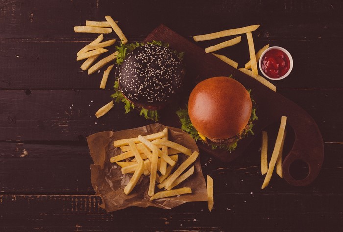 Two burgers and french fries on a wooden table