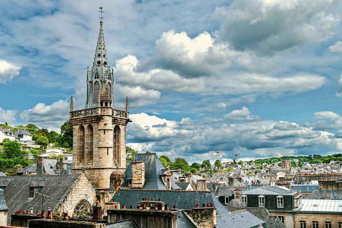 Town with church tower and rooftops under cloudy sky