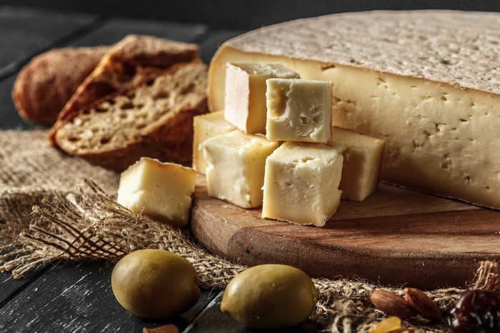 Cheese, bread, olives, and nuts on a cutting board