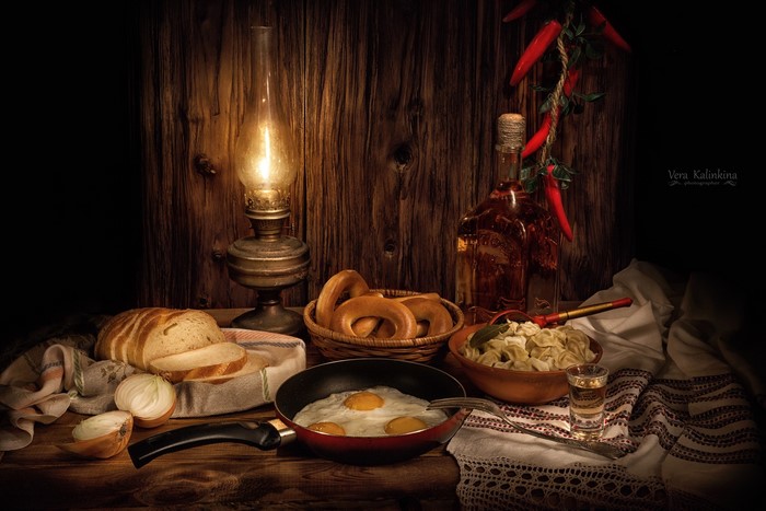 Still life with fried eggs, bread, pelmeni, and alcohol