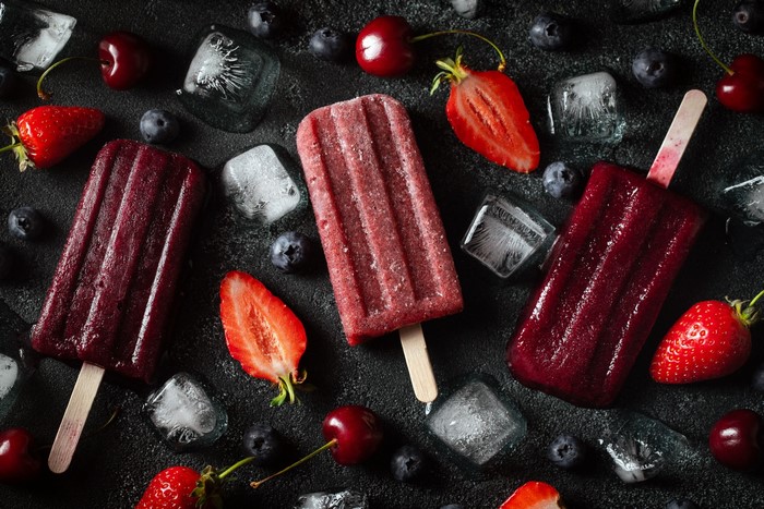 Assortment of fruit popsicles with berries and ice cubes